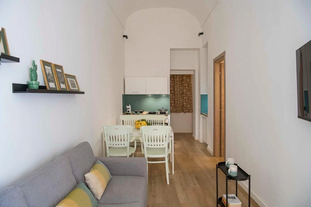 Soggiorno con divano, tavolo con limoni e cucina sul fondo