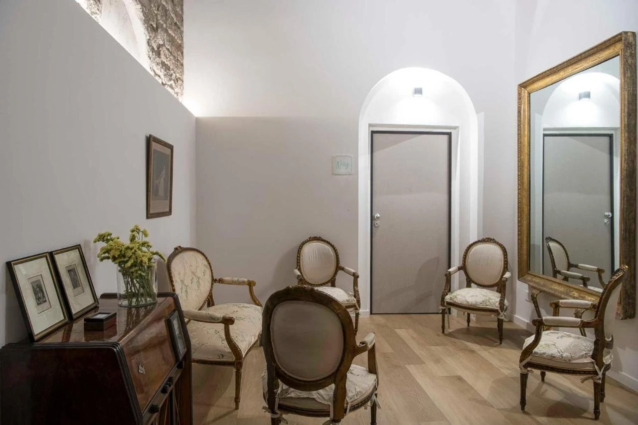 Ingresso con grande specchio dorato, poltroncine e porta ad arco
