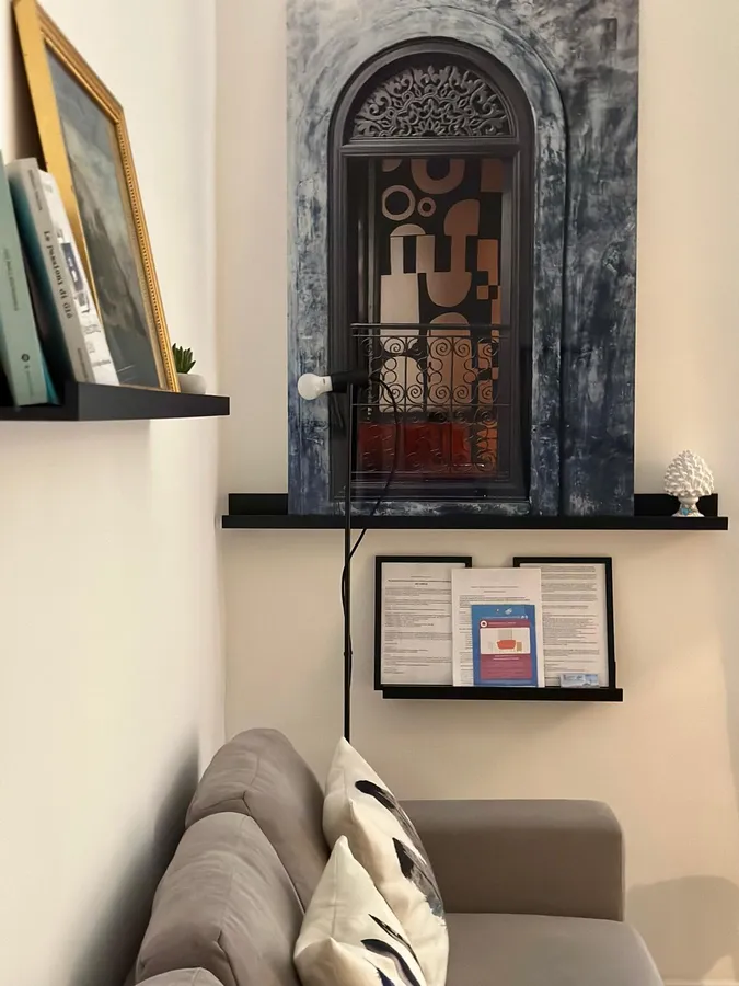 Una nicchia ad arco con un’opera d’arte, mensole con libri e il divano