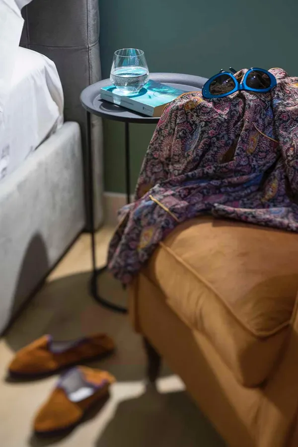 Il comodino e la poltrona, con un foulard e gli occhiali da sole
