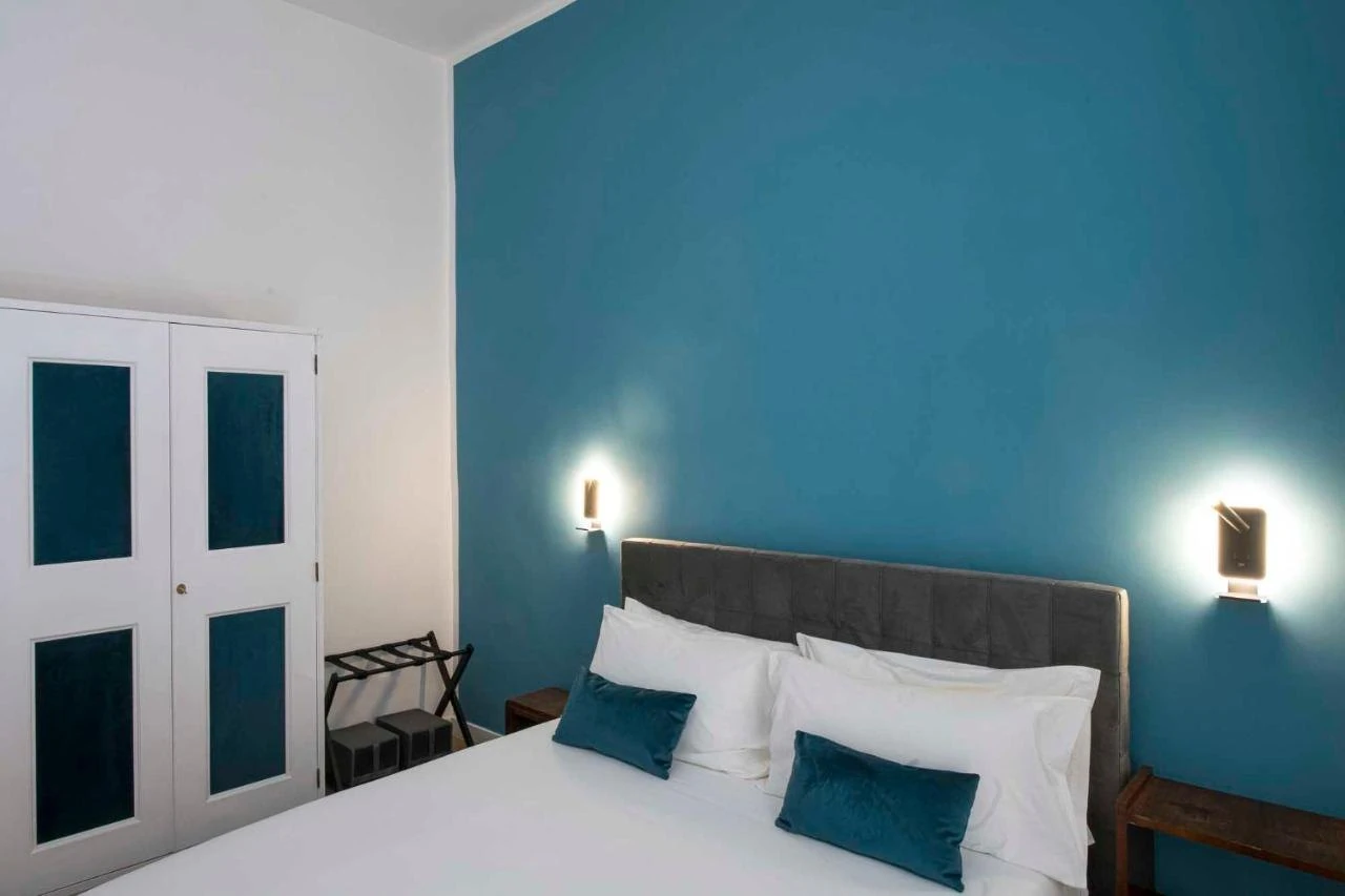 Il letto con le applique e la parete color petrolio